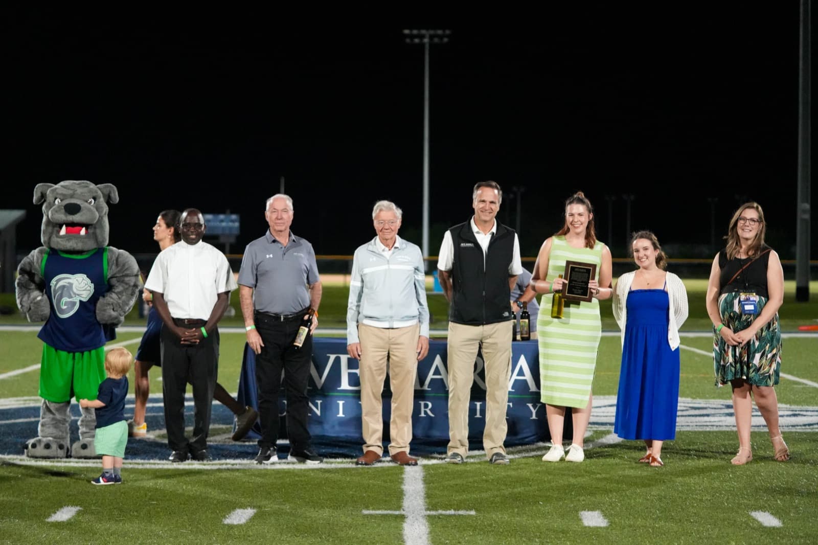 University leadership congratulating an Alumni Award honoree